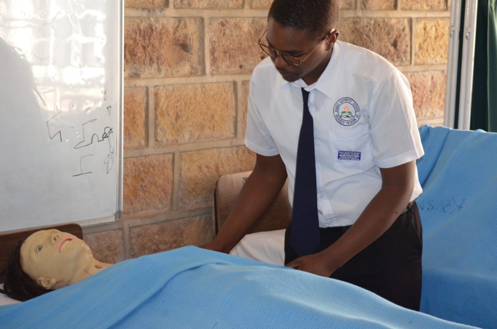 A KASMS student practising clinical skills with a training manikin